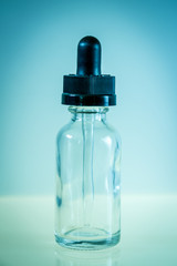 Glass dropper bottle on blue background
