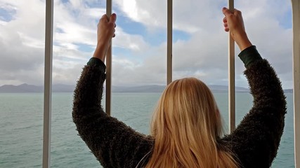 Blond Lady holding the bars and looking to sea and land