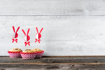 Drei Muffins mit Osterdeko vor Holzwand