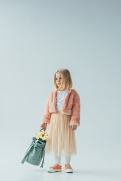 Cute Kid Holding Bag With White Tulips And Looking Away Isolated On Grey