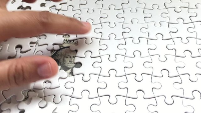 White Jigsaw Puzzle piece put into missing places with Dollar money background, Succeed in Business concept, Debt settlement concept.