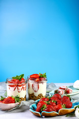 glass dessert with strawberries and cream Isolated on a blue background. Copy space. Healthy homemade dessert
