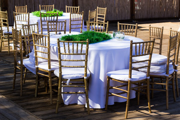 wedding exterior design photography of table with white tablecloth and empty dishes wooden furniture in outdoor yard environment