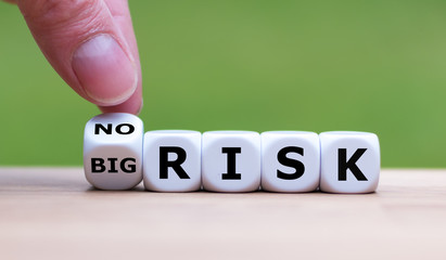 Hand turns a dice and changes the expression "big risk" to "no risk"
