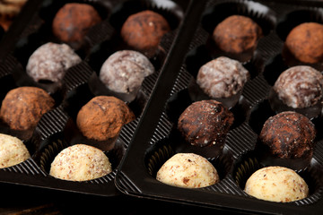 assorted chocolates. Candy balls of different types of chocolate in a box on a brown wooden table.