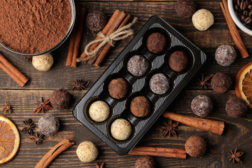 assorted chocolates. candy balls of different types of chocolate on a brown wooden table. cinnamon and almonds. top view