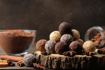 assorted chocolates. candy balls of different types of chocolate on a brown wooden table. cinnamon and cocoa