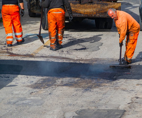 Worker regulate laying new asphalt to patch a bump in the road.