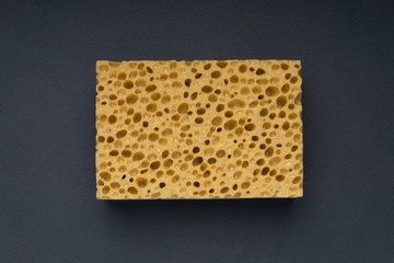 Close up view of cleaning sponge, mesh structure pattern on black surface. Yellow sponge close-up shot.
