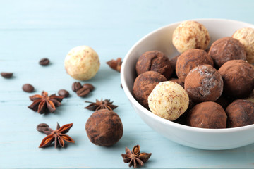 assorted chocolates. candy balls of different types of chocolate on a blue wooden table. cocoa, cinnamon, star anise and coffee beans.