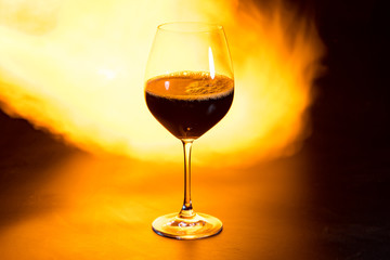 glass of red wine with fire in the background