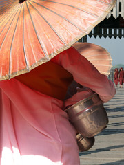 nun with pink robe and umbrella,walking on U bein bridge at Mandalay,Myanmar