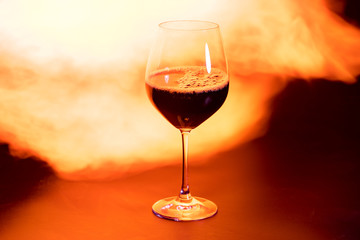 glass of red wine with fire in the background