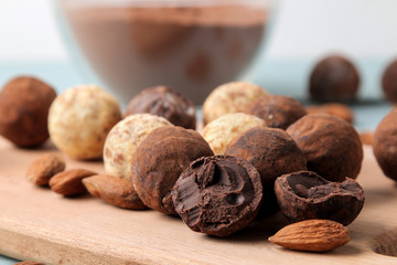 assorted chocolates. Candy balls of different types of chocolate on a wooden board on a blue wooden table. almond and cocoa