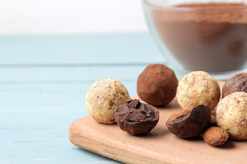 assorted chocolates. Candy balls of different types of chocolate on a wooden board on a blue wooden table. almond and cocoa