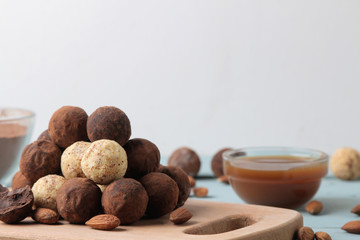 assorted chocolates. Candy balls of different types of chocolate on a wooden board on a blue wooden table. Caramel, Almond and Cocoa