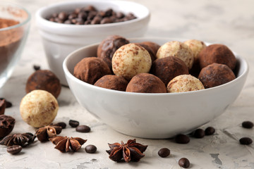 assorted chocolates. Candy balls of different types of chocolate on a light concrete background. cocoa, star anise and coffee beans