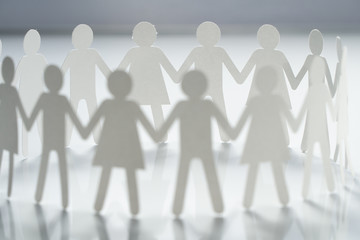 Circle of paper people holding hands on white surface. Community, brotherhood concept. Society and support.