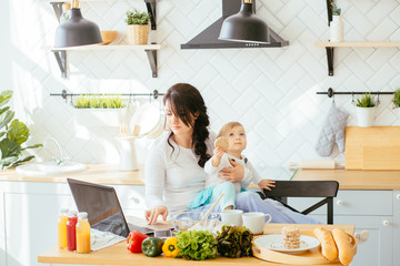 Working mother concept. Busy mm with baby in kitchen. Mother working at home. Super mom multitask...