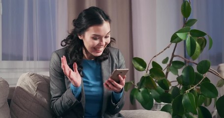 Surprised businesswoman using mobile phone and celebrating success at office