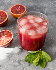 Fresh orange juice from red oranges with ice on the table.