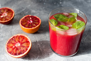 Fresh orange juice from red oranges with ice on the table.