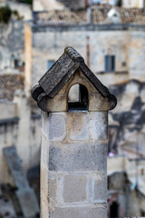 Summer day high-angle scenery street view of a smoked chimney over the amazing ancient town of the Sassi with blurred background of pattern of buildings in Matera, Basilicata, Italy