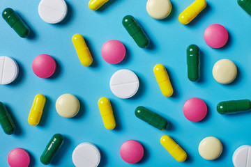 Multicolored pills on blue background. Pattern.