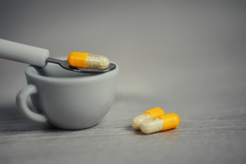 Table spoon of drugs drasticaly exagerated proportion on wooden table