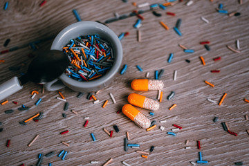 Concept medical photo depicting a cup of sugar related products with three pills representing anti sugar pills