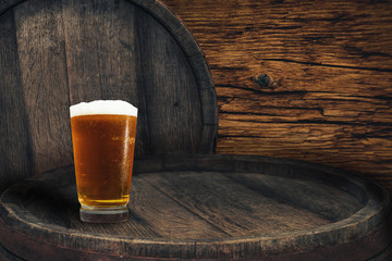 Wooden barrel and glass of beer on a barrel table of wood.