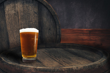 Wooden barrel and glass of beer on a barrel table of wood.