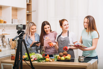 Healthy nutrition lifestyle. Blogging. Excited young females writing recipe. Smartphone video shooting.