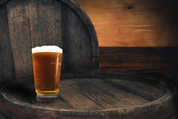 Wooden barrel and glass of beer on a barrel table of wood.