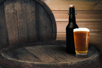 Wooden barrel and glass of beer on a old oak table of wood.