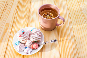 Romantic sweet breakfast concept. Green tea, lemon, meringue (cake). On wooden background.