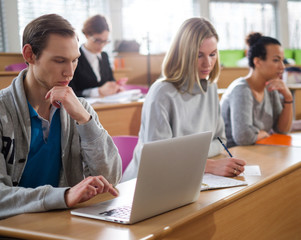 Man with laptop among students in an auditorium