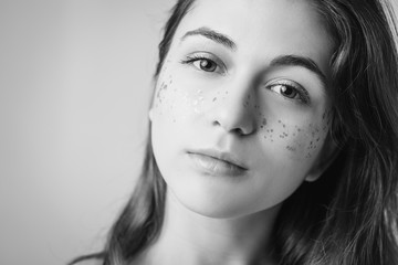 Fototapeta premium Young female portrait. Natural woman beauty. Fashion glitter freckles makeup. Copy space for text. Black and white.