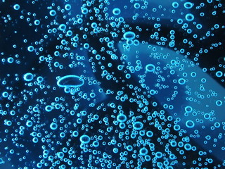 Close - up of air bubbles of different colors, in water isolated on dark background