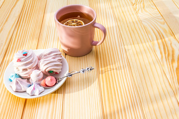 Romantic sweet breakfast concept. Green tea, lemon, meringue (cake). On wooden background.