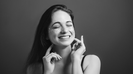 Young woman portrait. Fake female smile. Eyes closed. Black and white headshot.