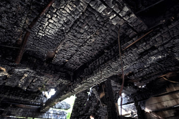 Burnt out house with charred roof trusses and burnt furniture