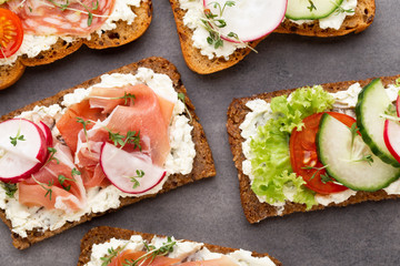 Sandwich with cereals bread and salami on dark marble background.