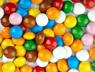Fototapeta na wymiar colorful candy on white background. Rainbow sprinkles for topping ice cream and cake. Small candies in colored chocolate glaze.