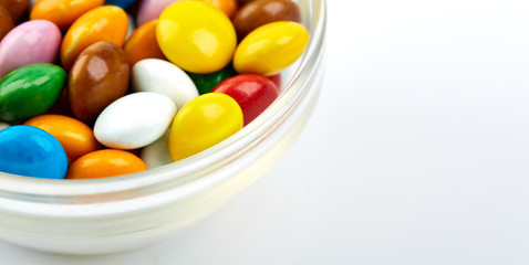 colorful candy on white background. Rainbow sprinkles for topping ice cream and cake. Small candies in colored chocolate glaze.