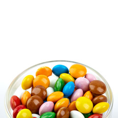 colorful candy on white background. Rainbow sprinkles for topping ice cream and cake. Small candies in colored chocolate glaze.