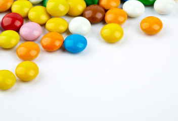 colorful candy on white background. Rainbow sprinkles for topping ice cream and cake. Small candies in colored chocolate glaze.