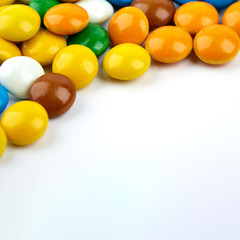 colorful candy on white background. Rainbow sprinkles for topping ice cream and cake. Small candies in colored chocolate glaze.
