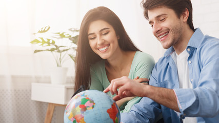 Tourists planning their vacation, looking at globe