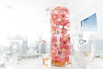 Salmon colored (light pink) orchids a water glass decorate on a table